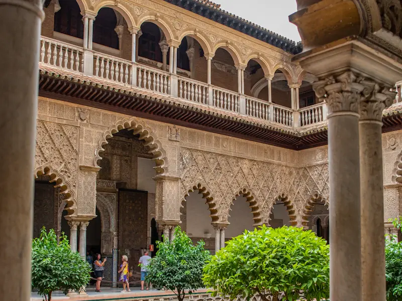 A courtyard of the Real Alcázar with carved arches and a garden