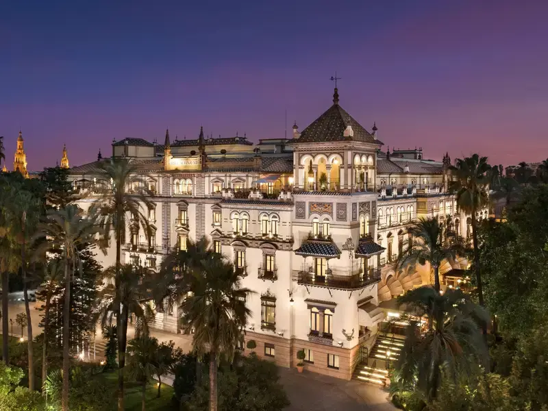 Hotel Alfonso XIII lit up at dusk, above its palm-filled garden