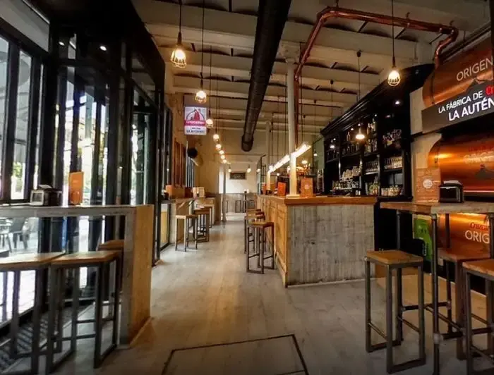 Inside Taberna La Auténtica: high tables and stools along the bar, big windows onto the street