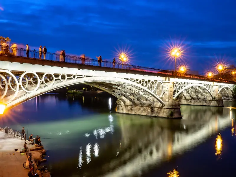 The iron arches of the Puente de Isabel II lit up at night